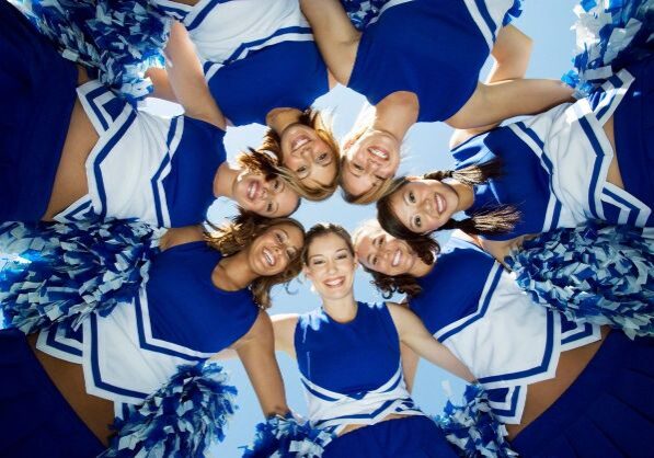 Blue color dressed cheerleaders smiling infront of a camera